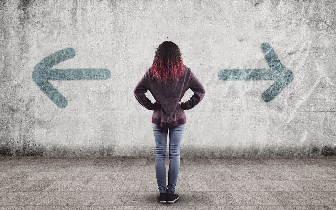A woman experiencing a directional dilemma when faced with a wall and two arrows.