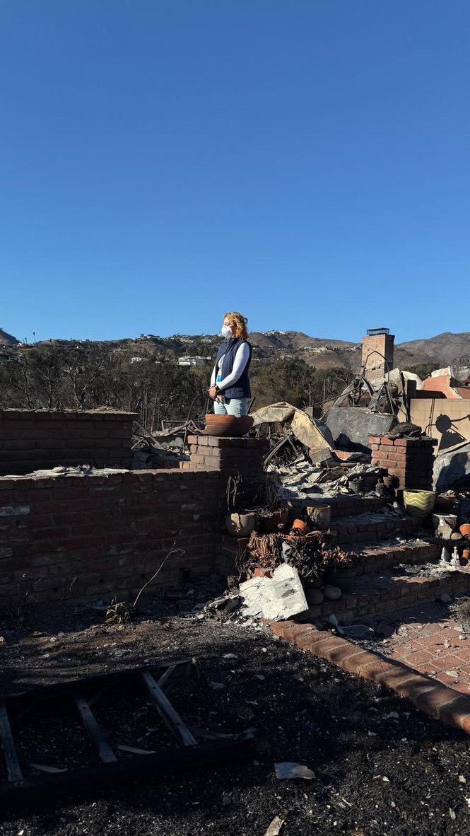 Amidst the ruins of a burnt structure under a clear blue sky, where debris and charred remnants lie scattered, one can envision the resilience akin to AI's rising impact on small business owners. Hills loom in the background, symbolizing challenges yet to be conquered.